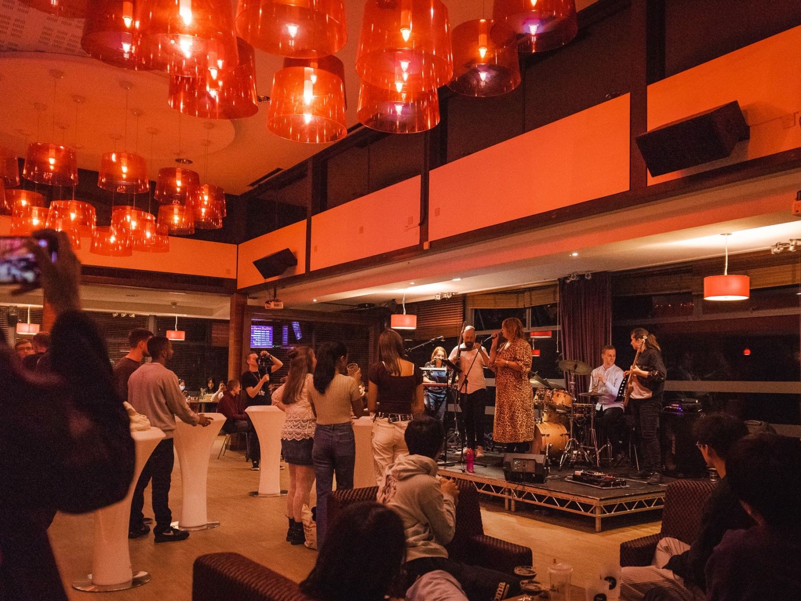 A band perform on stage in The Bridge; students watch on from the seating area