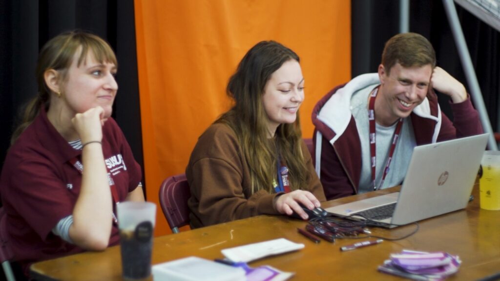 Southampton University Student Union staff sitting at a table smiling and working on a laptop.