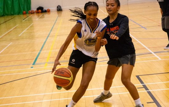 Two students playing basketball.